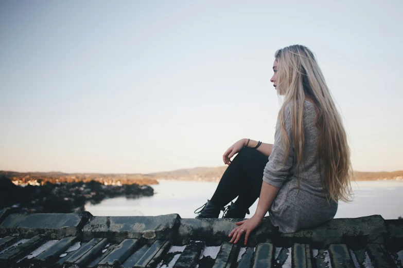 a woman sitting alone on the wooden fence in the background