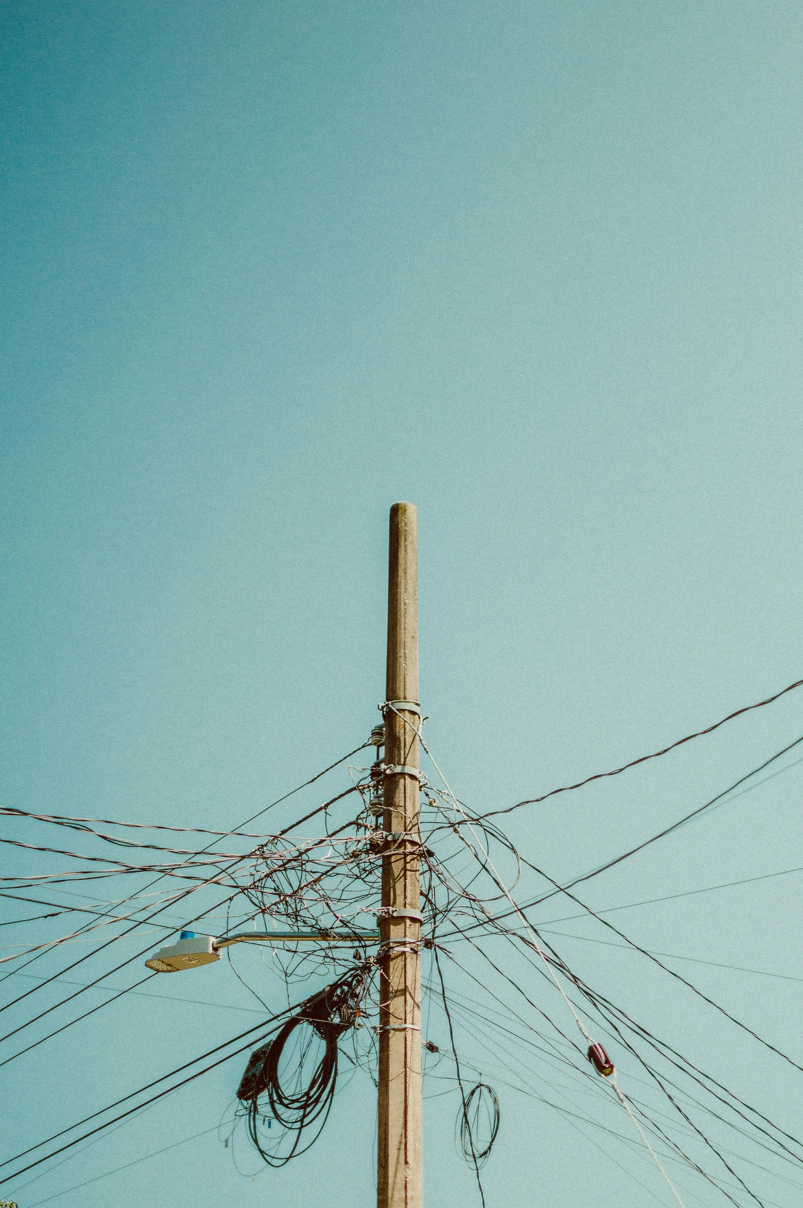 a street pole has lots of telephone wires all over it