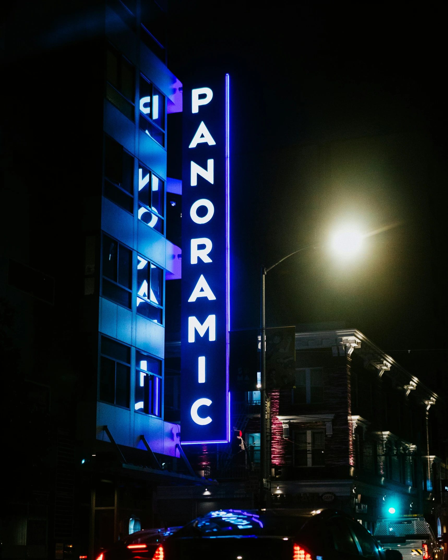 a neon sign lit up on the side of a tall building