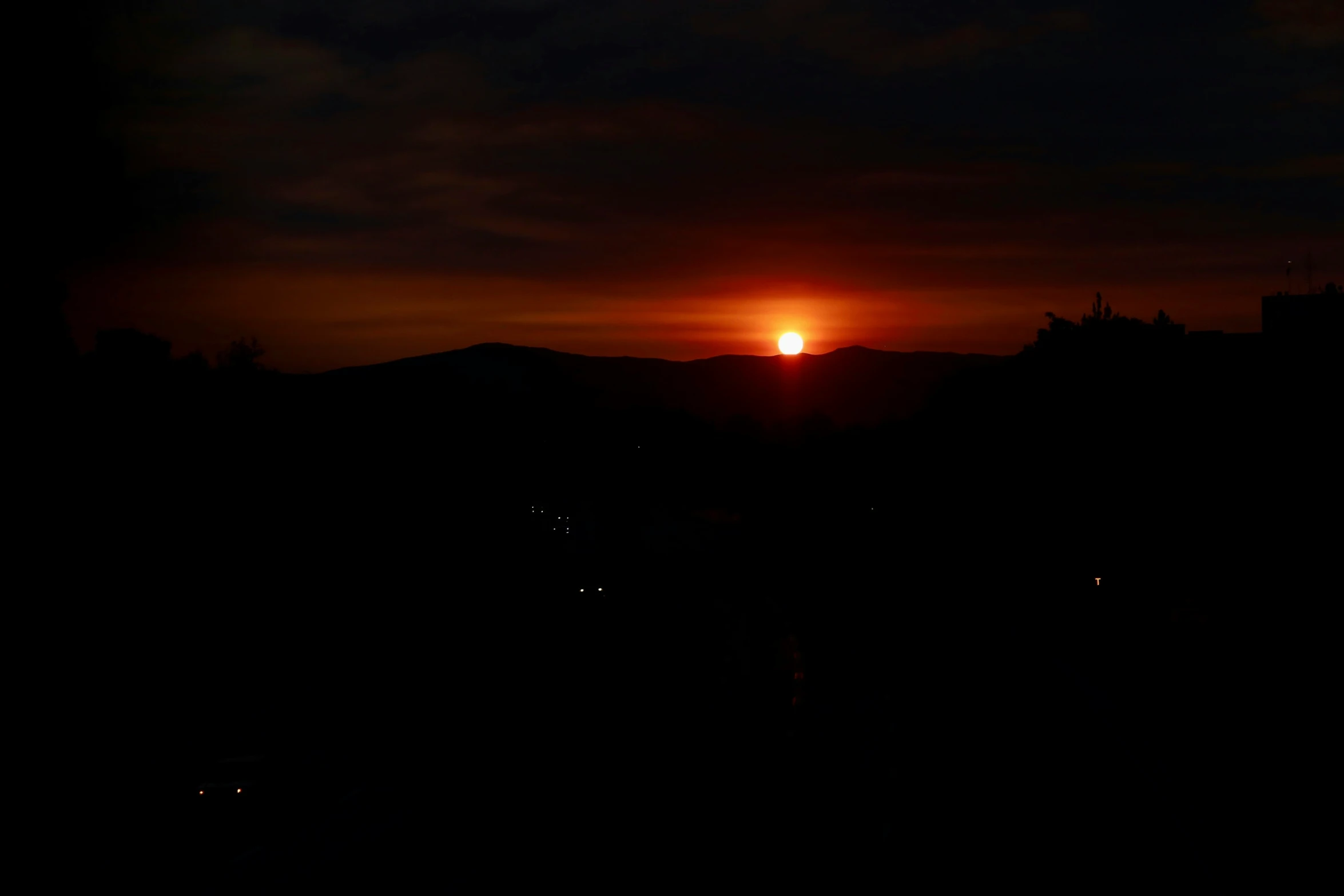 the sun setting on a hill over some trees