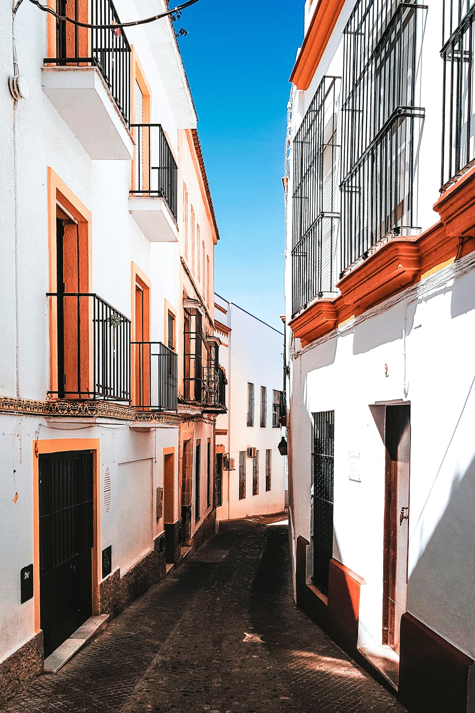 narrow city street with white buildings and balconies