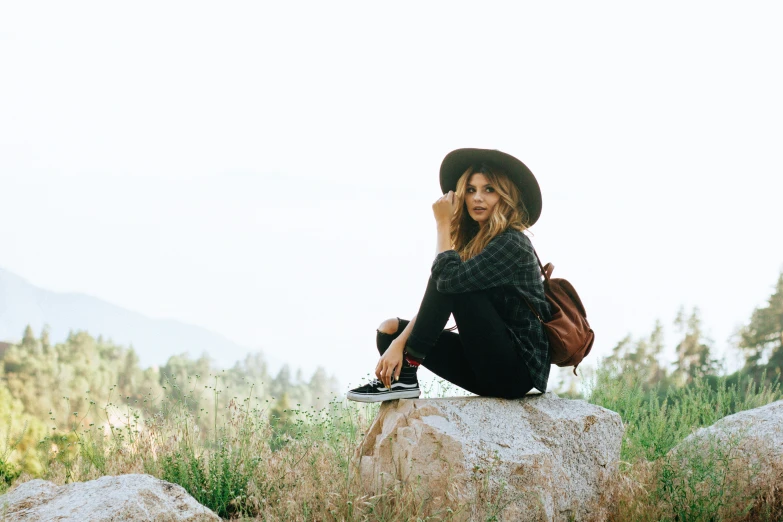 a woman sitting on top of a rock talking on a phone