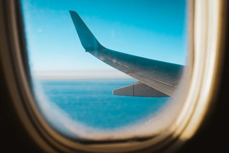 the wing of a jet airliner with ocean in background