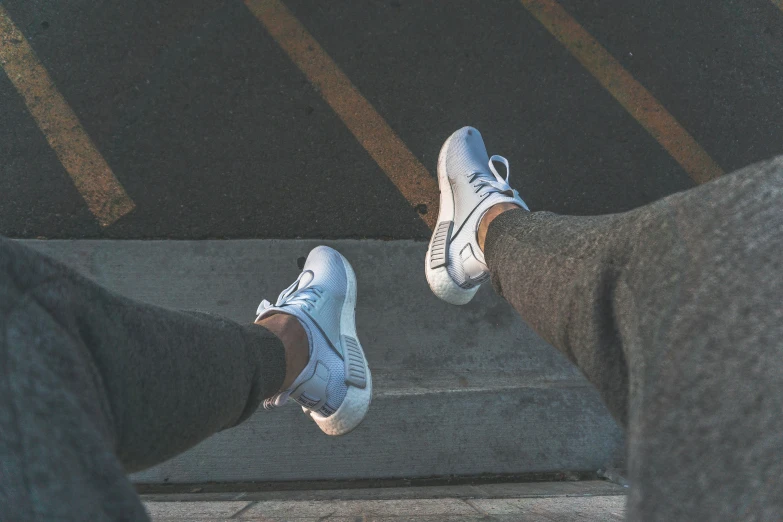 two feet wearing tennis shoes near the asphalt