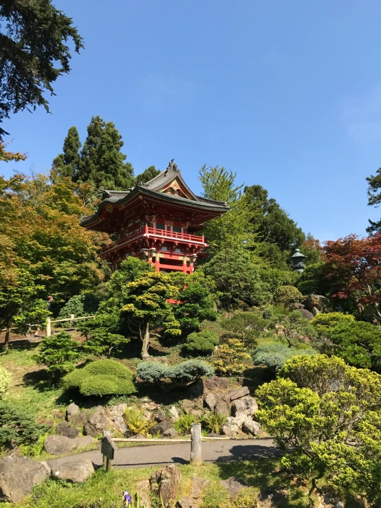 a red and black pagoda tower next to trees and rocks