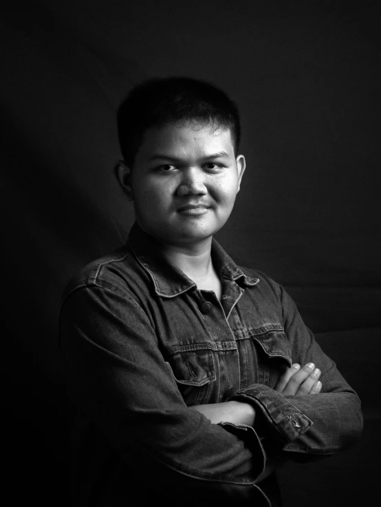 a man standing in a dark room with his arms crossed