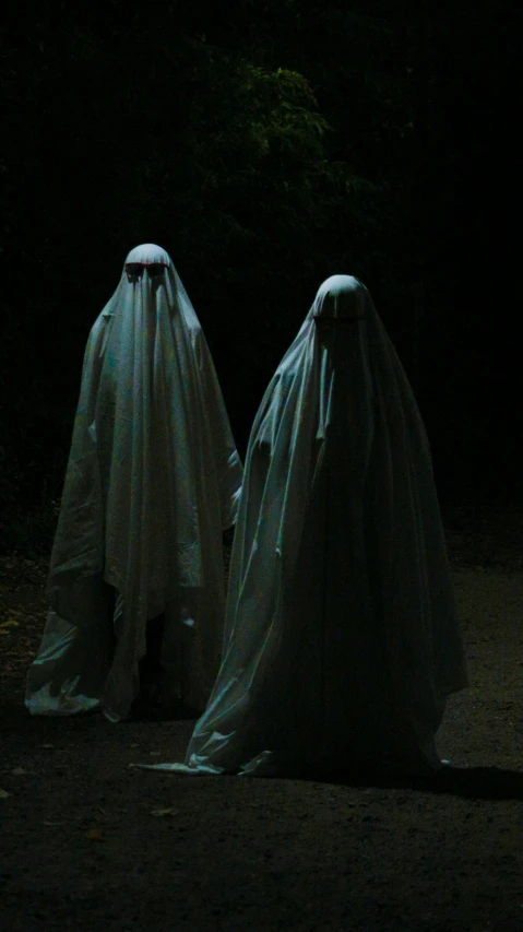 two people in white cloths stand at night