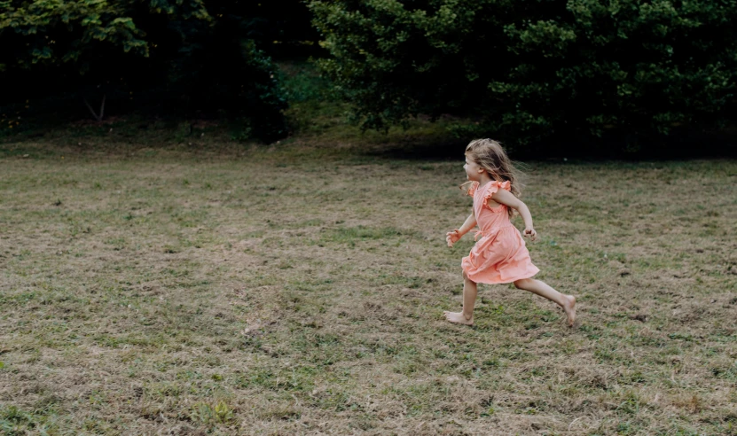 a girl in pink runs towards a frisbee