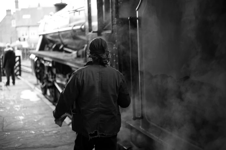 a person standing next to an old train at a station