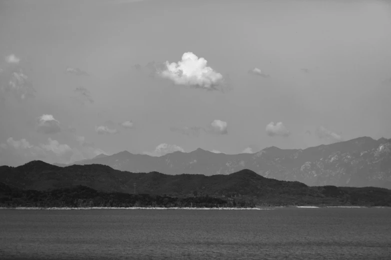 a distant mountain range across from water and trees