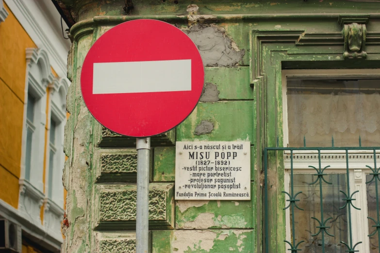 red and white sign on a metal pole near an old building