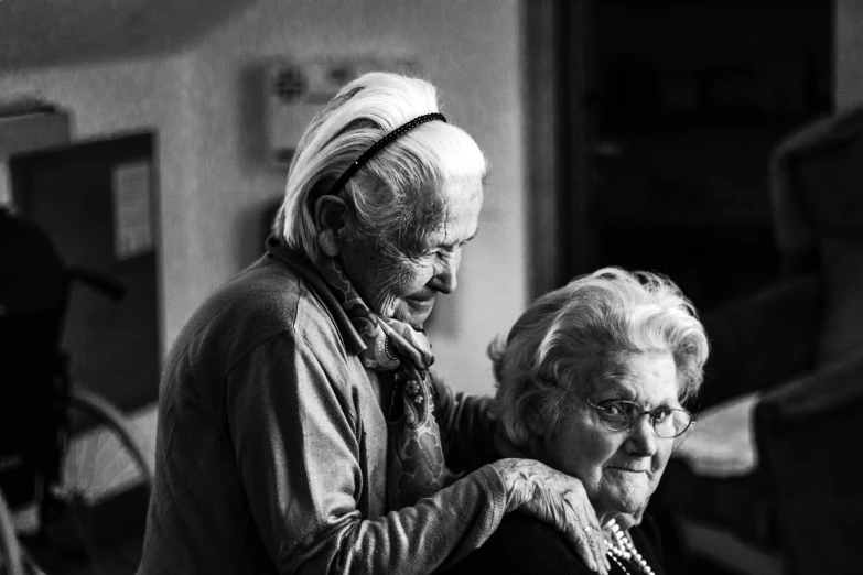 two women are standing next to each other with their hands on the back of the chair