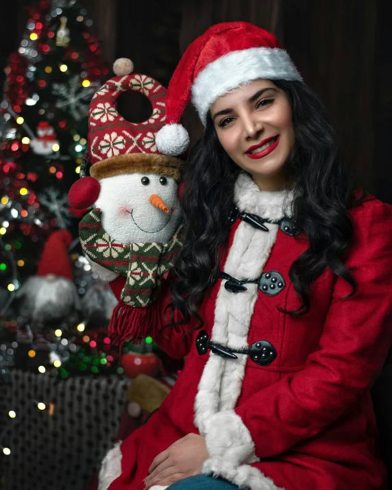 a smiling woman in a santa suit holds a snowman doll