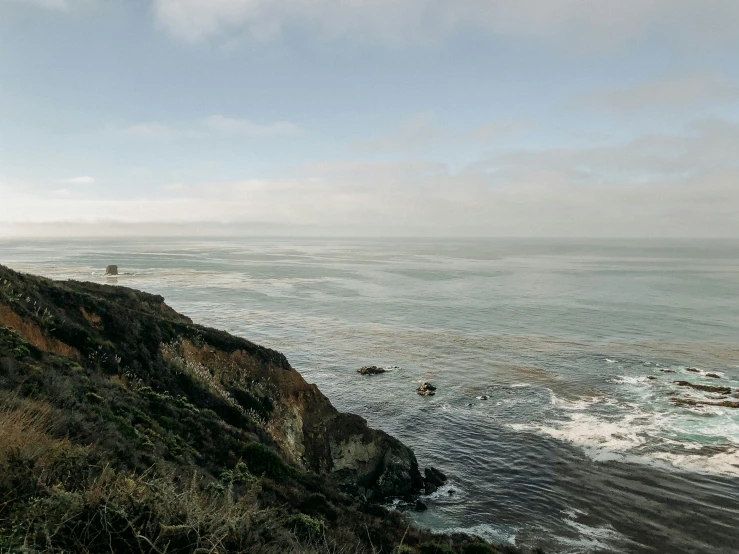 a couple of people hiking up a mountain near the ocean