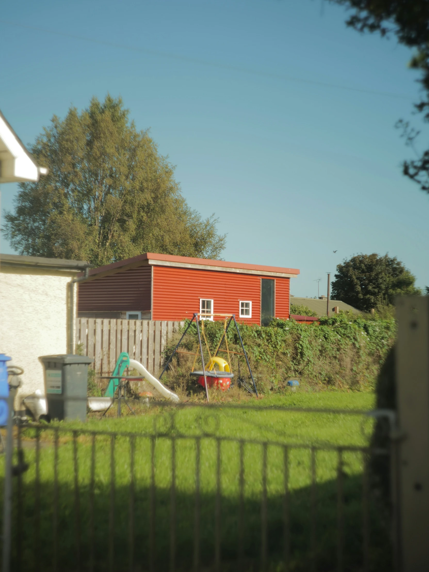 a red house with a playground area behind it