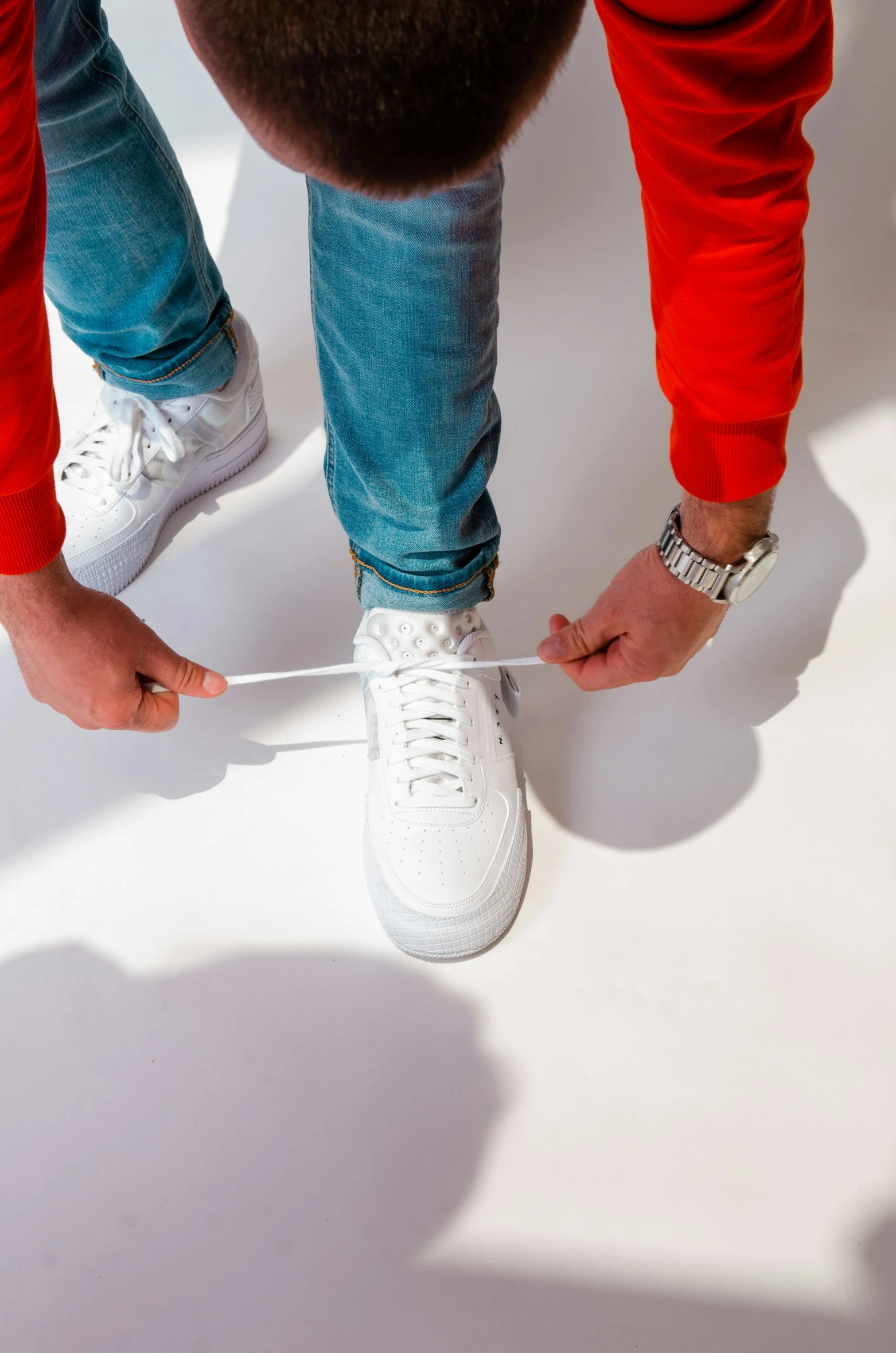 a person tying shoeslaces with white shoes