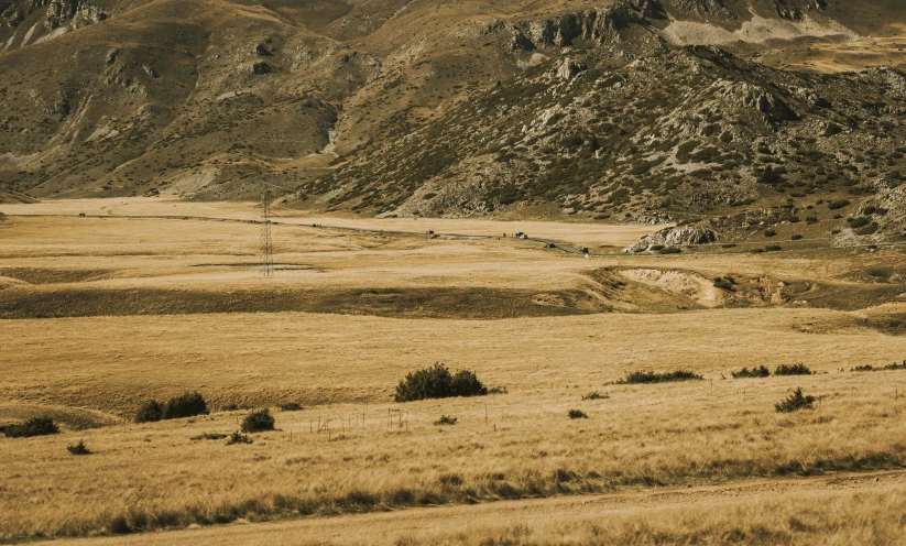 an empty hill surrounded by dry grass and hills