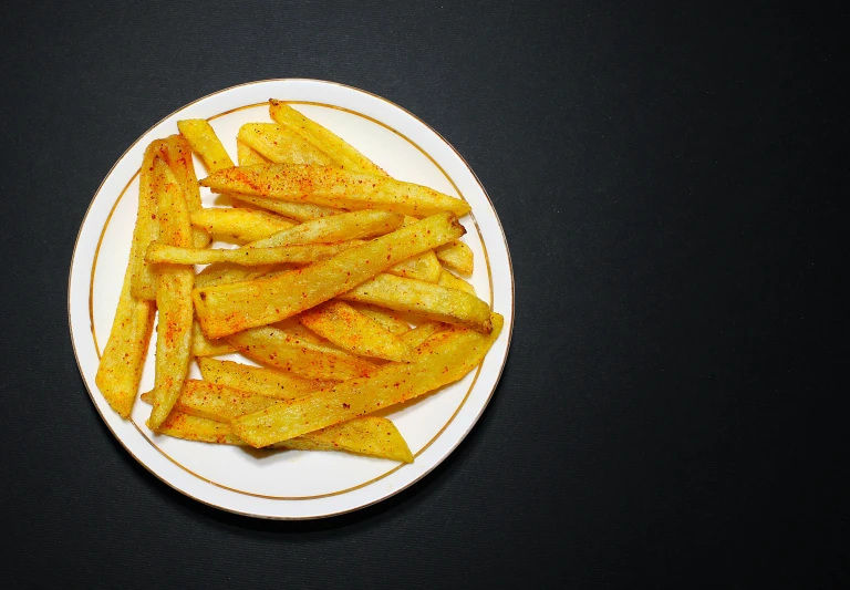 baked french fries sit on a plate, on a black table