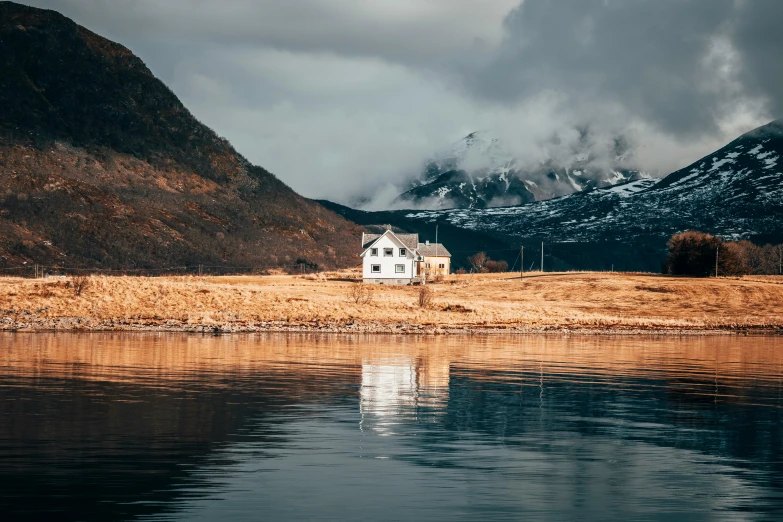 a house next to the water with a mountain in the background