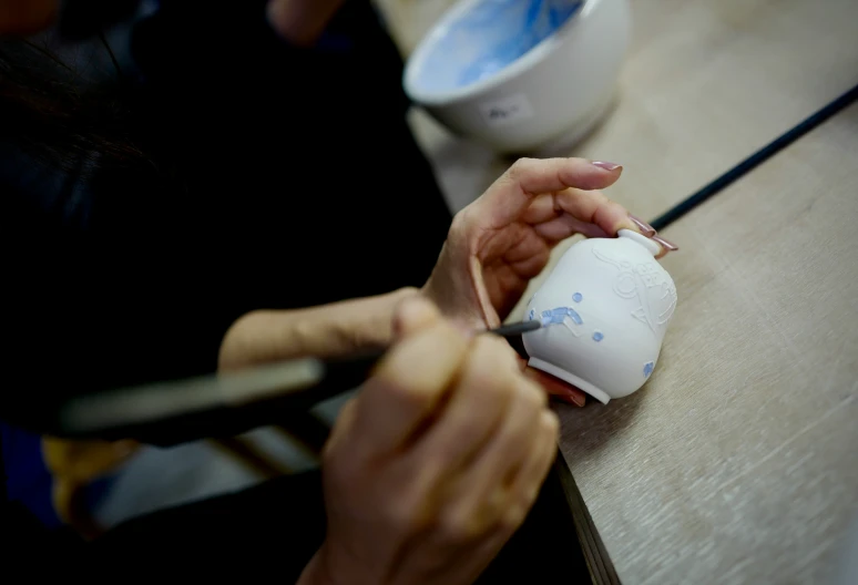 a hand holding scissors  paper on top of a table