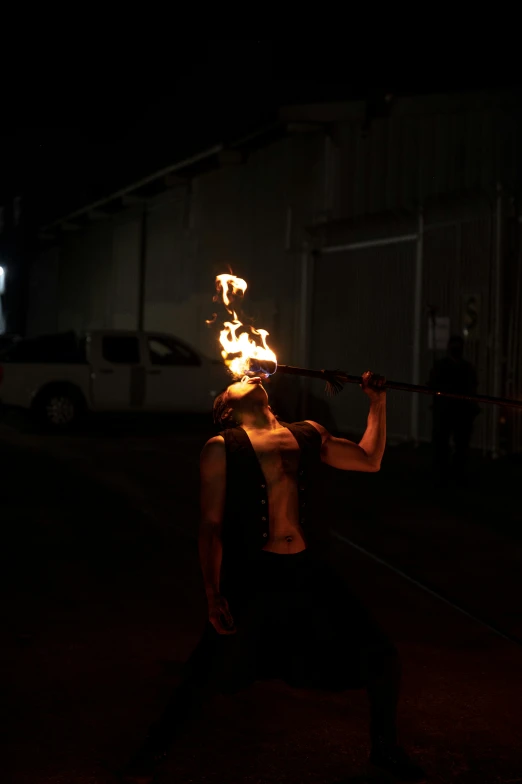 a man standing on top of a street holding a fire torch