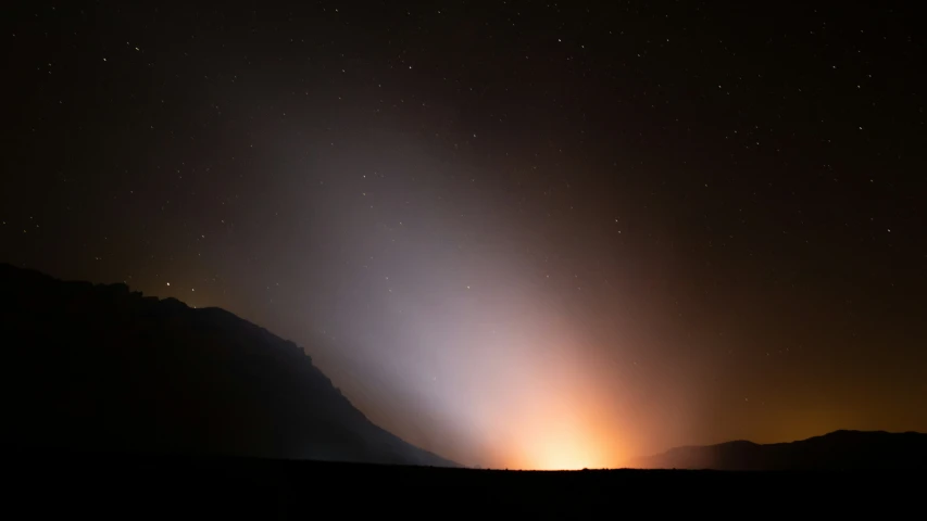 a big hill with some sky lite up in the background