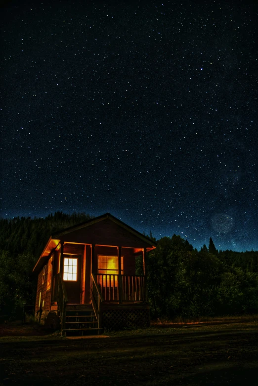 a cabin with the sky full of stars lit by a bright window