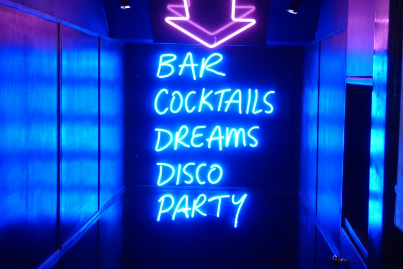 a neon sign inside a hallway with a bar cocktails dreams disco party