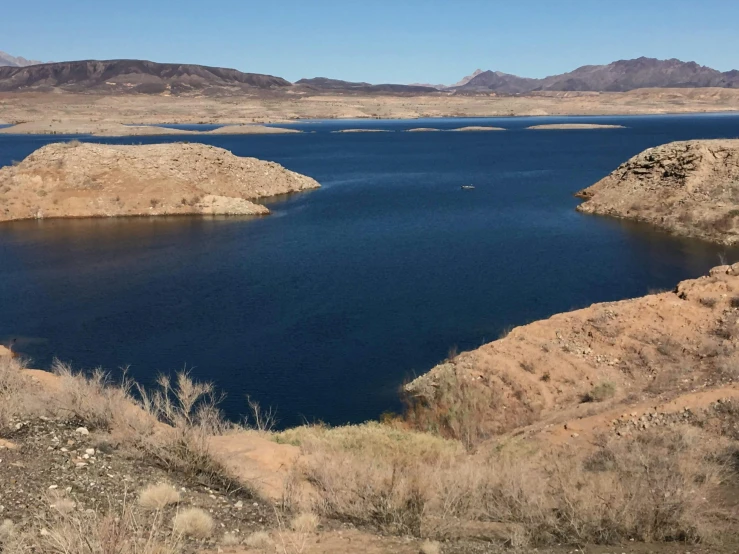 a blue lake in a large field next to a mountainous area