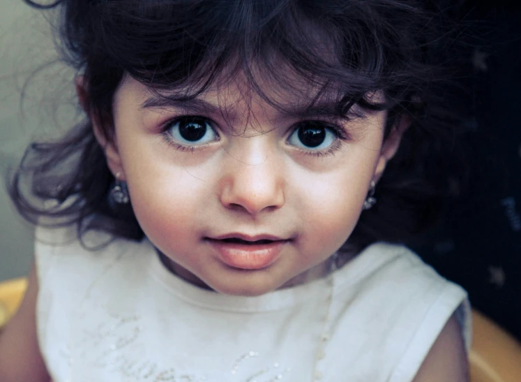 a child in a white dress has dark hair