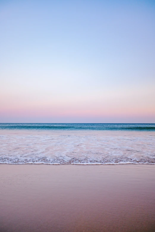 two people walking along the shore of an empty beach