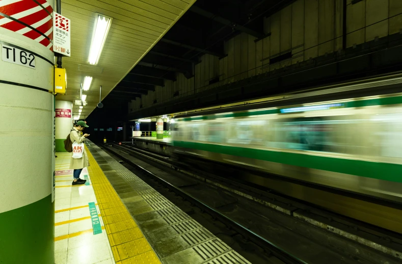 a person stands at the end of the subway platform