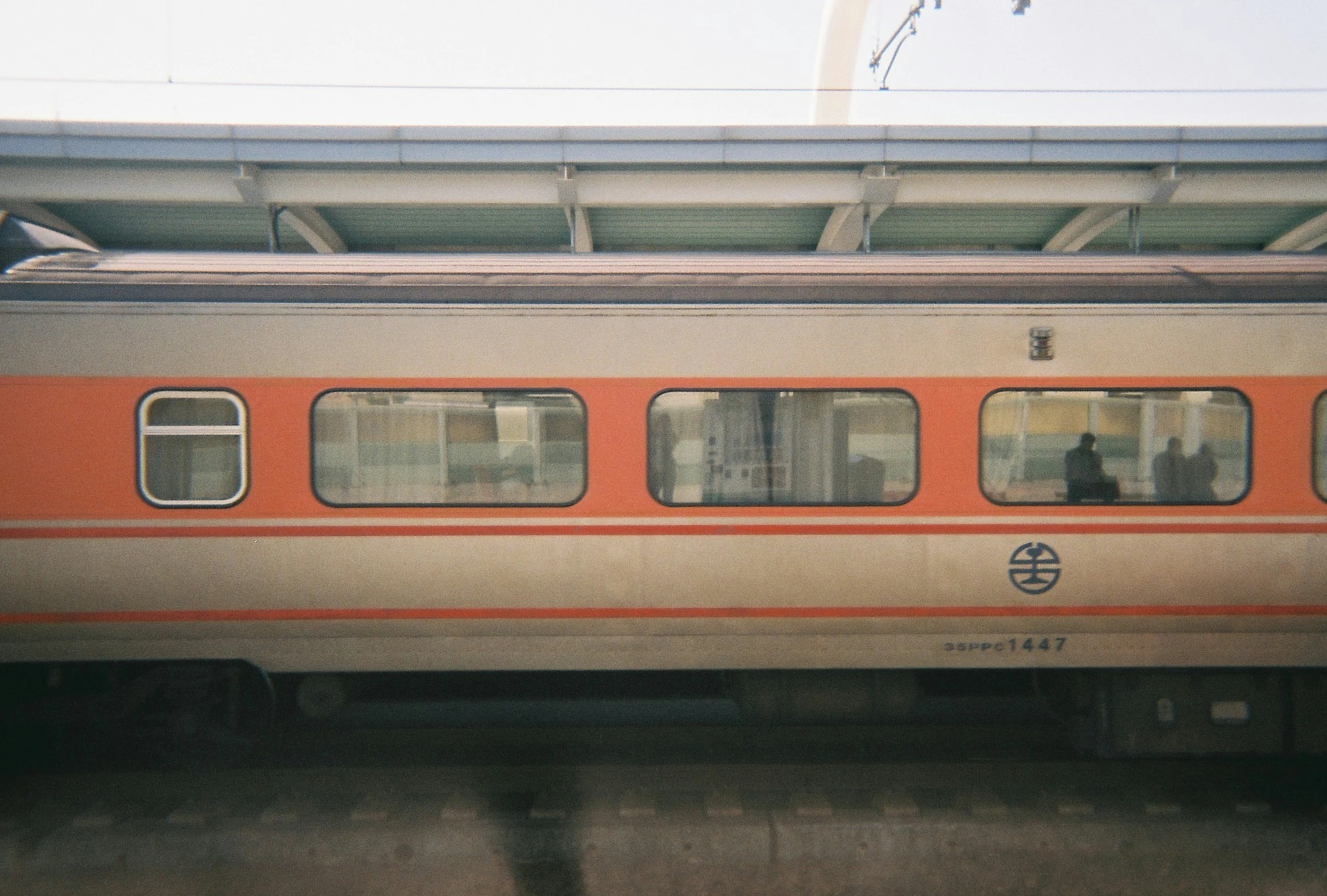 an orange and gray train is pulling into the station