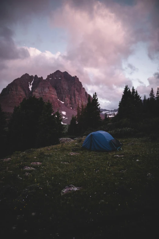 a tent pitched in the field with a cloudy sky