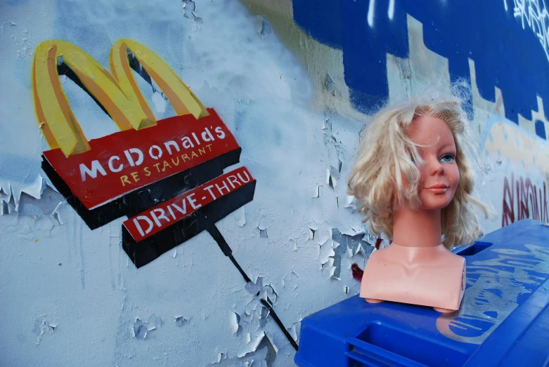 a fake head next to a mcdonald's drive thru sign and a plastic trashcan