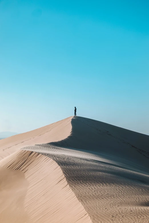 a lone person stands on a large dune