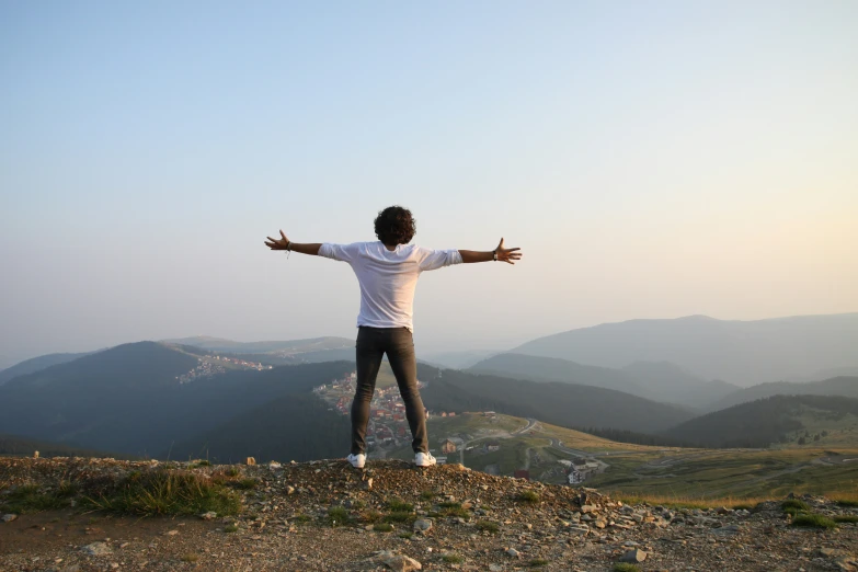 a man standing on top of a mountain on his arms stretched out