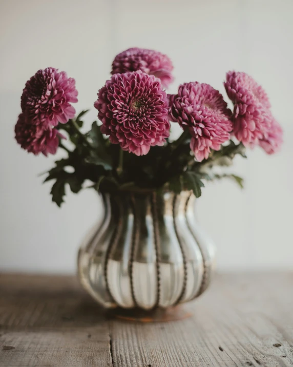 the pink flower is in the vase on the table