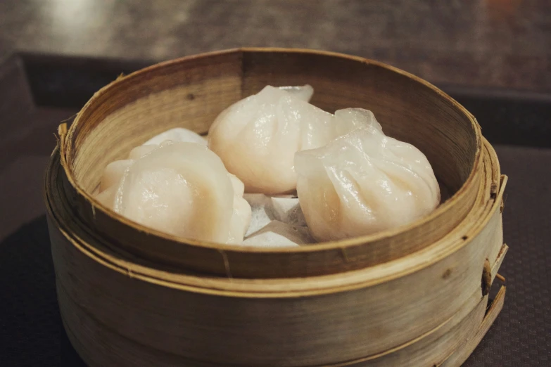 two steamed dumplings in wooden bucket on table