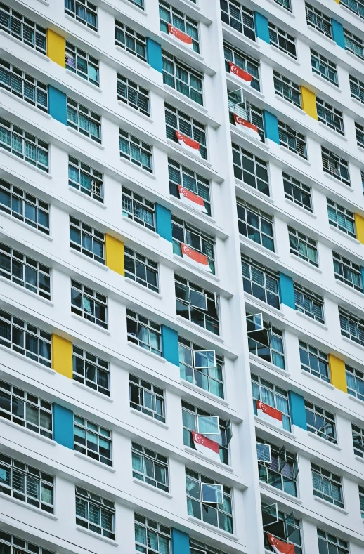 a tall white building has windows with colored bars on the sides