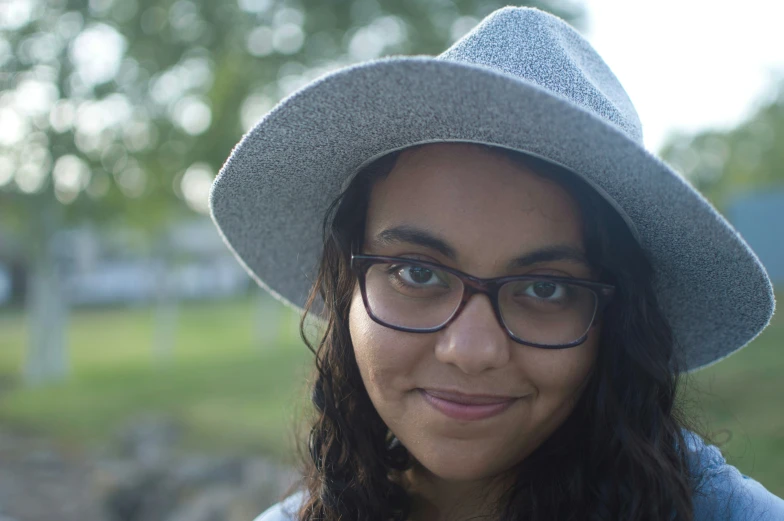 woman wearing glasses and a hat posing for a po