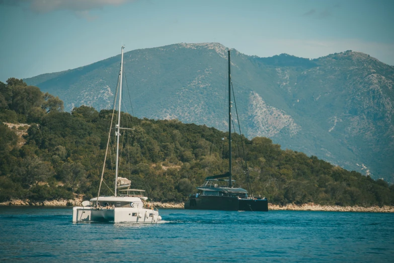 a boat and a yacht sailing on the water in front of trees