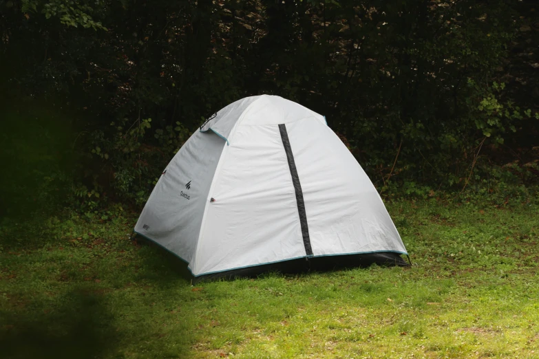 a tent pitched on grass with trees in the background