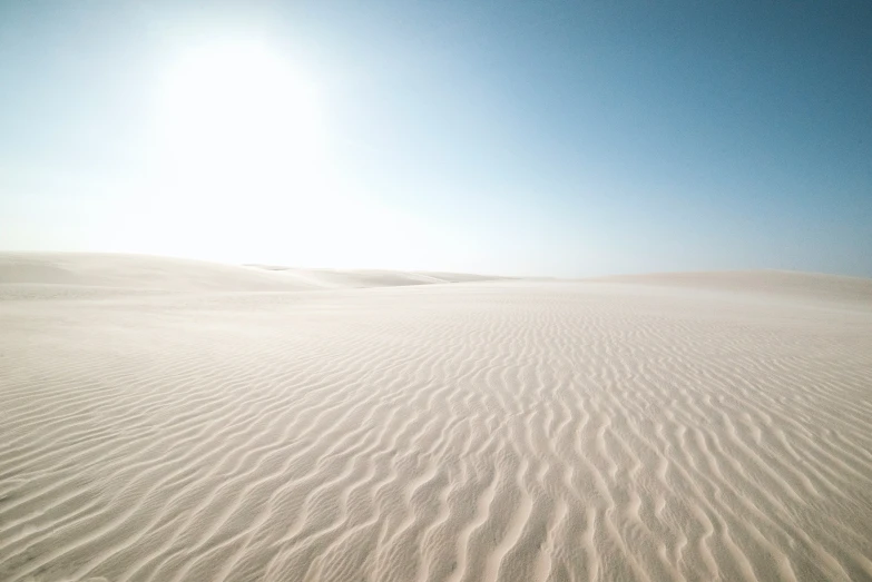 an empty sandy beach with some people standing in the sand