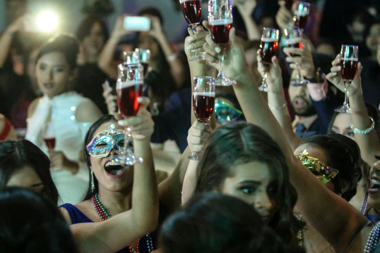 a bunch of people raising their glasses at a party