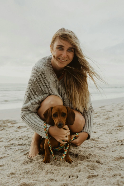 woman holding a dog at the beach in her hands