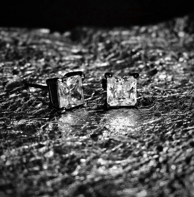 the square shaped silver and crystal earrings are sitting on snow
