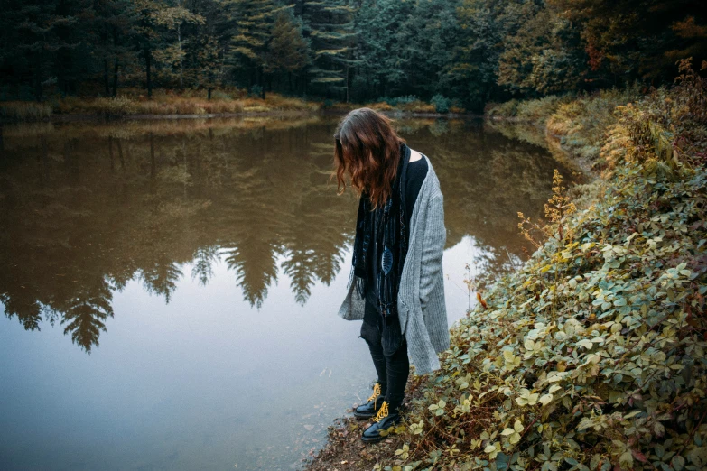 a woman standing by the water with her back turned