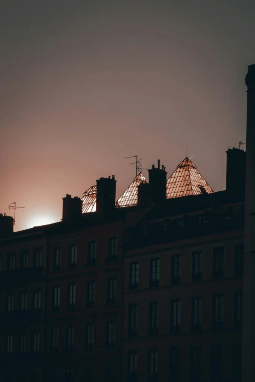 an orange glow shining in the background above many tall buildings