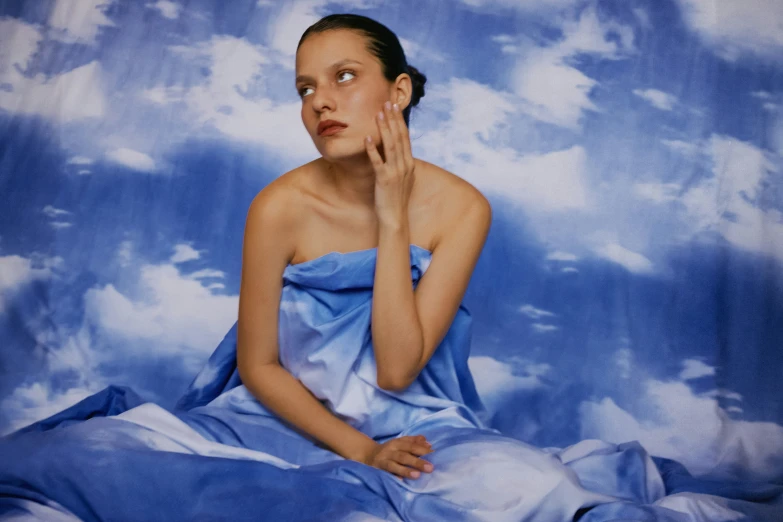 a painting shows a woman sitting on a cloudless background